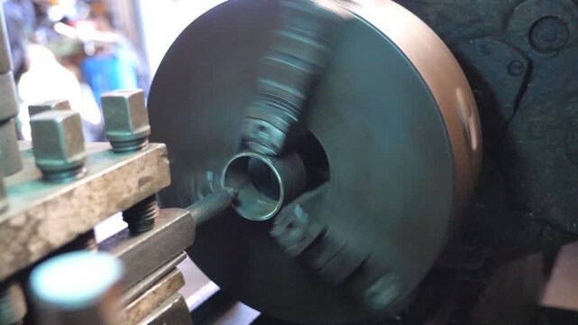 Close up of milling machine in action. View on rotating old workbench in garage or workshop. Mechanic or turner using lathe for metal processing. Slow motion