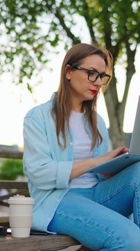 Woman sitting in the park with laptop after work day in the office.