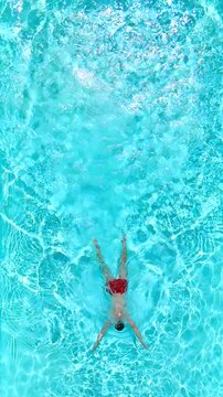 Aerial view as a man dives into the pool and swims.
