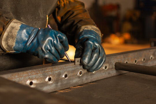 Close up of industrial worker marking metal piece for fabrication