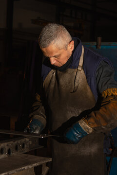 Industrial worker organizing metal pieces for welding in workshop