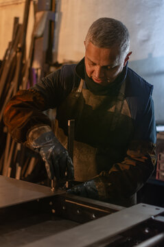 Industrial welder securing metal piece with clamp before welding