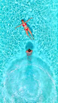 Top down view as a man dives into the pool while woman lays on her back