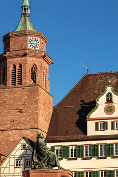 Church tower and Johannes Kepler monument against blue sky in the historic centre of Weil der Stadt, Germany.