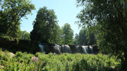Scenic Waterfall in Green Forest Park on Sunny Summer Day © Creatura Studio