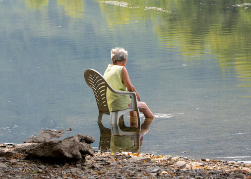 Seniorin k&uuml;hlt sich w&auml;hrend einer Hitzewelle im Rhein ab und genie&szlig;t die Erfrischung im Wasser
