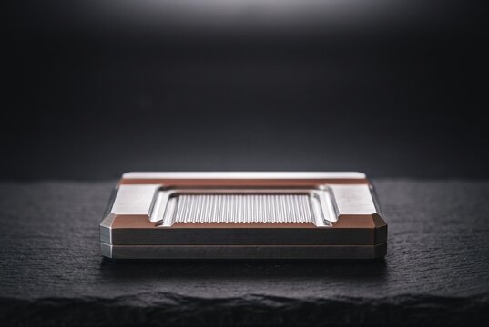 Modern metallic EDC fidget slider gadget with precision CNC machined details displayed on a dark slate surface under studio lighting