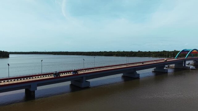 Aerial view of vehicles crossing a bridge over a wide river in Kerala, India
