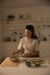 African American woman preparing salad at kitchen countertop, using cutting board and chef's knife © wavebreak3