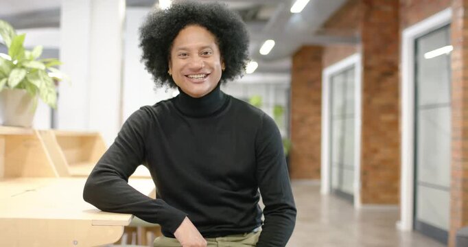 African American man in black sitting at office desk smiling at camera while recording interview