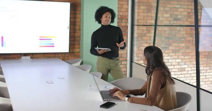 African American coworkers using bar chart in office, using tablet, typing on laptop, copy space