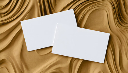 Fototapeta premium Two clean white paper cards arranged diagonally on textured golden wavy background. One card slightly overlapped on, offering blank space for text design. Minimalist visual for branding mockups,