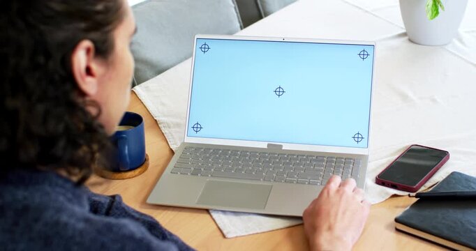 African American man sitting left at table adjusting hand on laptop seeing blue markers, copy space