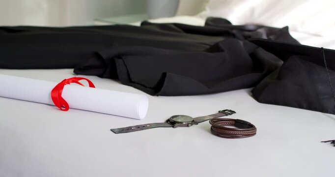 Rolled paper, watch and braided bracelets are resting on table as camera is moving, revealing plant