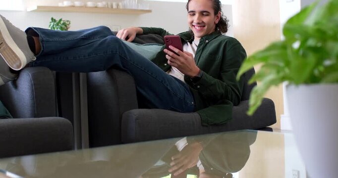 African American man reclining at home with red-phone reacting while camera rising over glass table