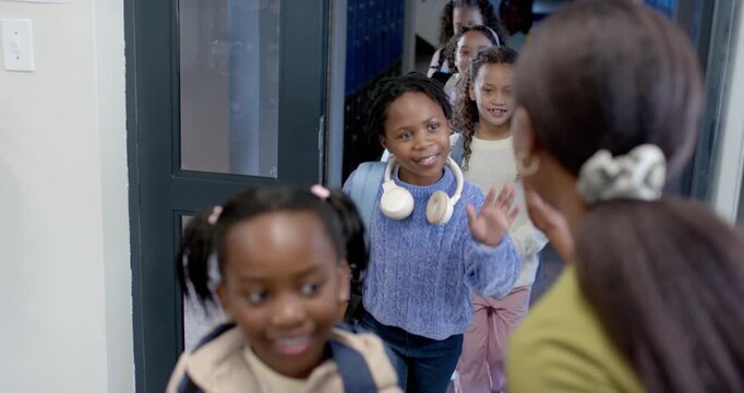 Female greeter right giving highfives as school girls peeking open glass door entering, copy space