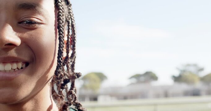 African American teen male smiling, widening mouth after head turn on field with braids, copy space
