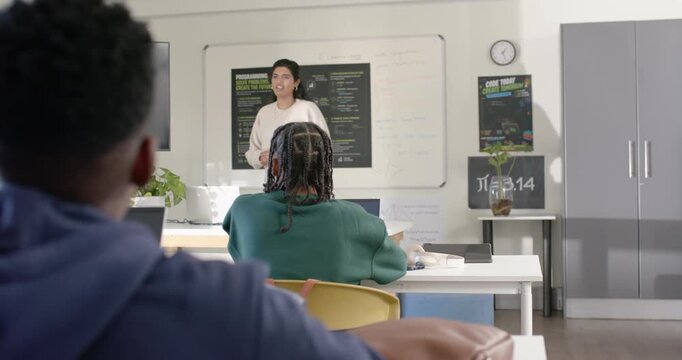 Indian teacher leading African American teen males in class, pointing to board to explain Pi poster