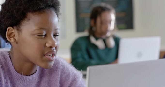 African youth in class smiling then focusing as camera panning right, male typing laptop for lesson