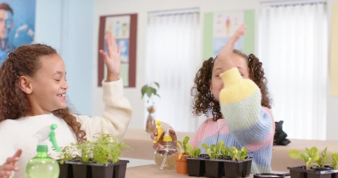 African American teen girls, pastel sweater girl using sprayer on trays in class, causing high-five