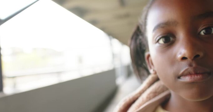 African girl child opening eyes, smiling, leaning into camera on balcony in blanket, copy space