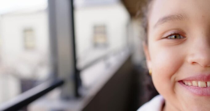 African American child after eyes shut, opening, smiling, widening grin on balcony rail, copy space