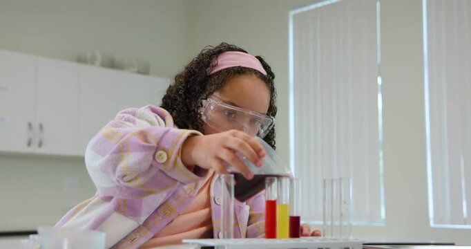 African American teen wearing goggles picking beaker pouring liquids into tubes for lab class