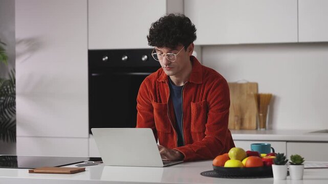 Young male programmer feeling tired and taking glasses off during work on laptop