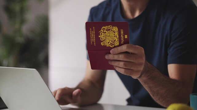 Man holding British passport while applying for a visa on laptop, online service