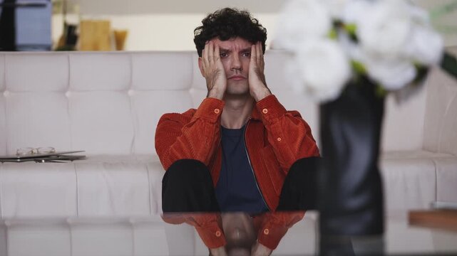Broken-hearted young man touching his head, thinking about relationship problems