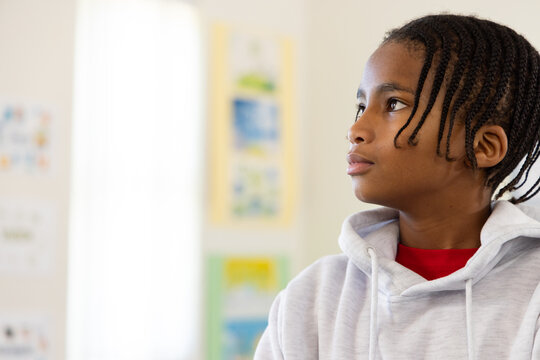 African American teenage male looking right at school wearing gray hoodie, braids, copy space