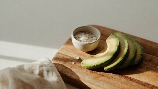Sliced avocado with coarse salt on wooden cutting board with captures fresh sliced still life copy space