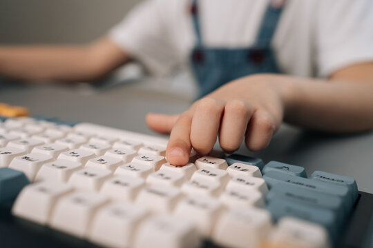 Childs finger presses key on computer keyboard. Kid learns about technology, coding, gaming. Modern digital education and early development concept. Soft light with shallow depth of field focus.