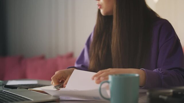 Asian woman checking utility bills and calculating expenses, planning budget
