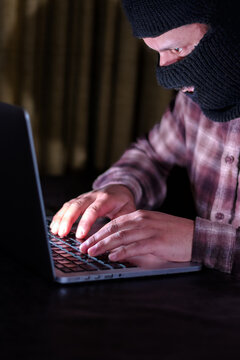 Computer hacker wearing a mask using a laptop for data breach and cyberattack