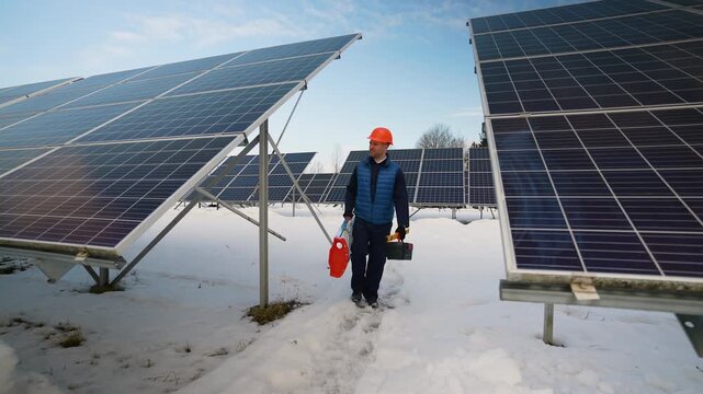 Maintenance engineer walking in a snowy solar panel farm