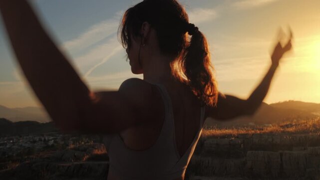 Woman practicing mindful movement on a hilltop at golden hour sunset, embracing freedom and serenity for wellness and self discovery purposes