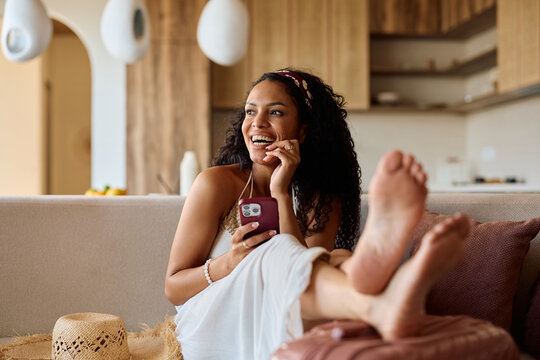 Happy black woman using smart phone vacation rental in summer.