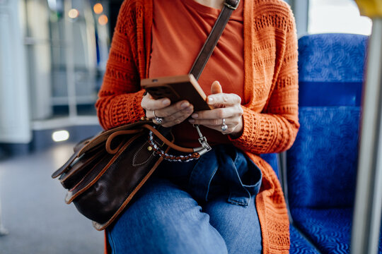 Connected female commuter using smartphone while seated inside modern city tram