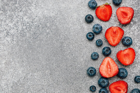 Fresh strawberries and blueberries arranged on a gray background for a healthy snack idea or recipe
