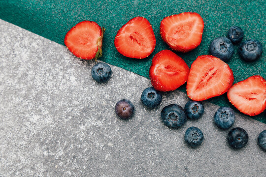 Fresh strawberries and blueberries on a textured surface during daylight hours