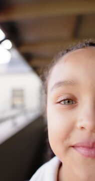 Vertical video: African American child opening eyes noticing camera smiling in hoodie on balcony