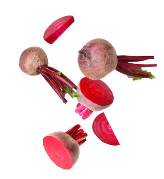 Sliced and whole beets flying in air against white background