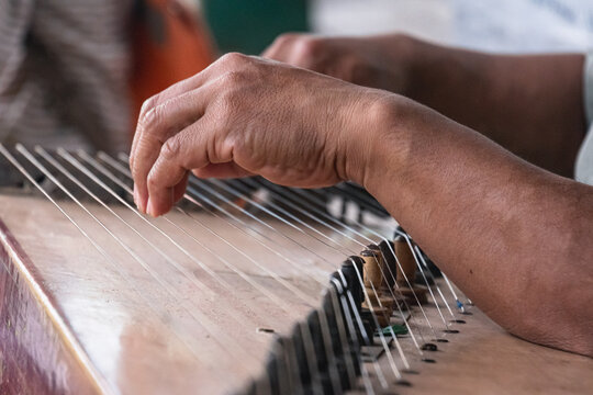 Close-up of a hand plucking the strings of a traditional Sundanese kecapi musical instrument