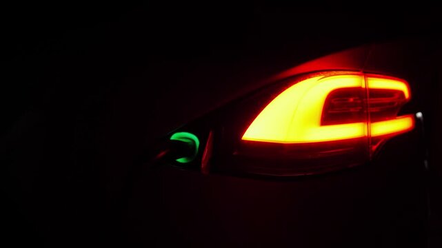 Electric car charging at evening. Power connector inserted into EV automobile. Process of recharging of e-vehicle battery. Environmentally friendly zero emission auto. Clean energy filling technology