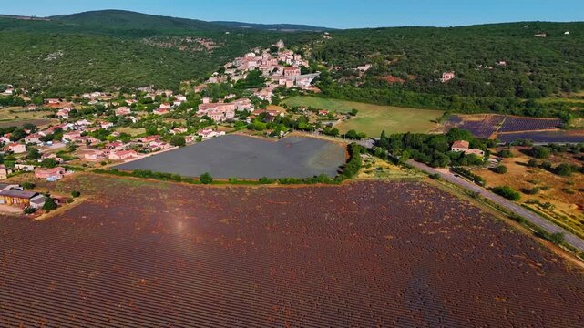 Aerial drone view Simiane-la-Rotonde among the mountains and blooming purple lavender fields. Provence-Alpes-Cote d'Azur region. High quality 4k footage
