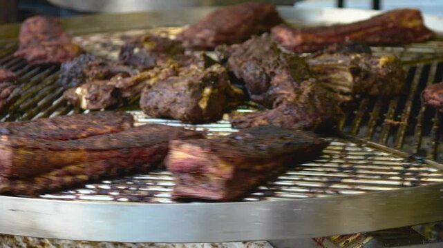 Juicy Meat Pieces Rotating and Sizzling on Large BBQ Grill
