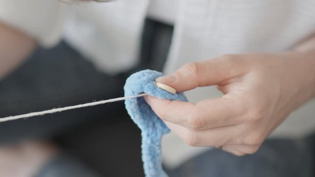A hand skillfully crochets with plush blue yarn, capturing the essence of handmade creativity and slow living. This image emphasizes mindful crafting and the beauty of textile artistry