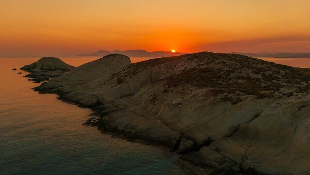 A beautiful sunrise over the dramatic shoreline of Mandrakia on the Greek island Milos. Calm water and vibrant colors. 