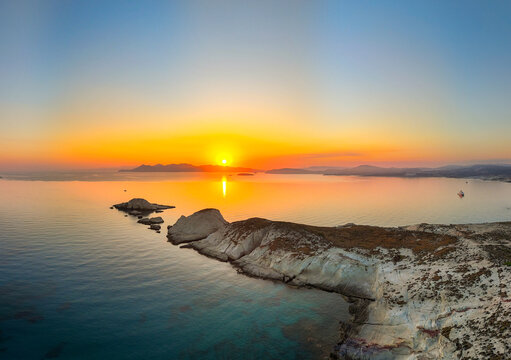 A beautiful sunrise over the dramatic shoreline of Mandrakia on the Greek island Milos. Calm water and vibrant colors. 